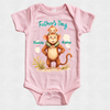 A light pink short-sleeve baby bodysuit with a custom Father's Day graphic. The graphic features an illustration of a brown monkey carrying a small baby on its back, with the text 'Father's Day' in teal, 'Daddy' next to the monkey, and 'Kaley' next to the monkey's head.
