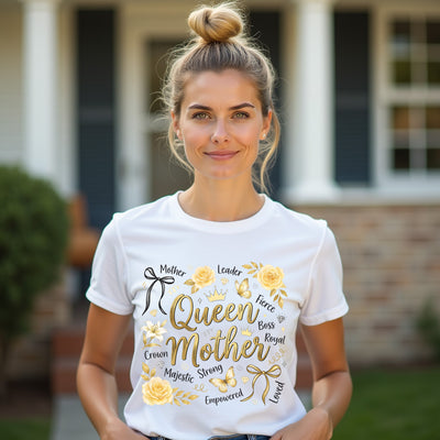 Woman wearing a white t-shirt with gold text queen mother and graphics outdoors.