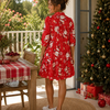 Woman in a red floral dress standing on a patio with a Christmas tree and table.