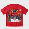 A red short-sleeve crewneck t-shirt featuring a colorful graphic print for 'Book Week Quest Comic City' on a light gray textured background.