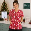 Person wearing a red Christmas-themed scrub top in a medical setting with festive decorations.