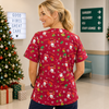 Person wearing a red Christmas-themed scrub top in a hospital setting with a decorated tree and gift boxes.