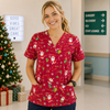 Person wearing a red Christmas-themed scrub top in a hospital setting with a decorated tree and gift boxes.