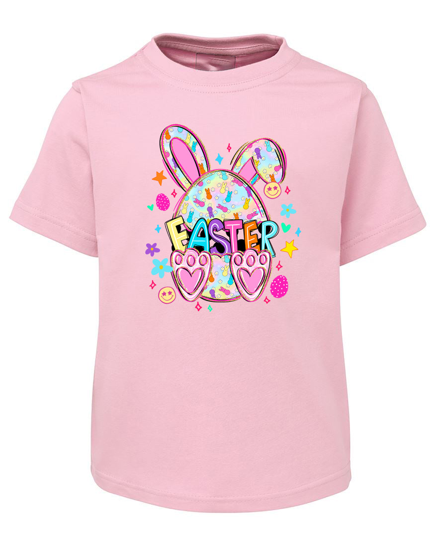Pink t-shirt with Easter design featuring bunny ears, eggs, and text on a white background