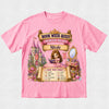 A pink short-sleeve crewneck t-shirt featuring a detailed graphic print for a 'Book Week Quest Princess Palace' themed party. The graphic includes an illustration of a princess in a pink gown, a castle, a vanity mirror, and a checklist titled 'CAN YOU FIND?'.