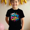 Child wearing a black t-shirt with colorful text 67, standing against a neutral background with balloons.