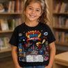 A young girl smiling in front of a blurred bookshelf, wearing a black graphic t-shirt with a colorful 'Book Week Quest Comic City' print.