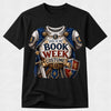 A black short-sleeve crewneck t-shirt featuring a detailed graphic print of a medieval knight's costume armor with the text 'THIS IS MY BOOK WEEK COSTUME!'. The graphic includes blue and white armor, gold accents, a sword, and a shield, displayed against a light gray background.