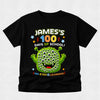 A black short-sleeve kids' t-shirt with a colorful graphic on the front reading 'James's 100 Days of School! 100 Eyes Learning' and featuring a green multi-eyed monster character, shown against a light gray background.