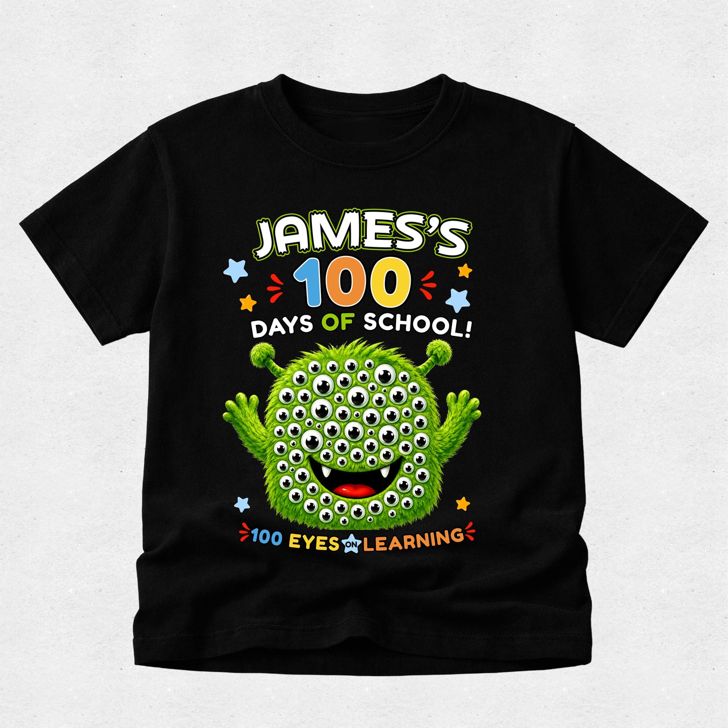 A black short-sleeve kids' t-shirt with a colorful graphic on the front reading 'James's 100 Days of School! 100 Eyes Learning' and featuring a green multi-eyed monster character, shown against a light gray background.