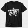 A black short-sleeve crewneck t-shirt with a white graphic text print that reads 'A CONVERSATION CAN MAKE A DIFFERENCE' with a small heart detail, displayed on a light gray textured background.