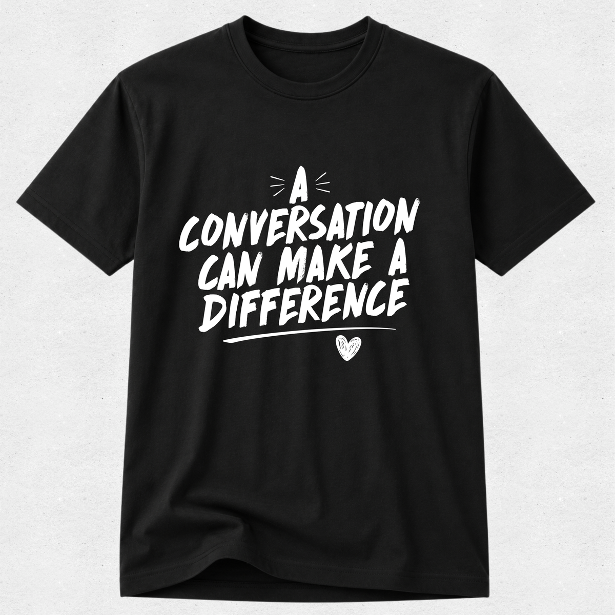 A black short-sleeve crewneck t-shirt with a white graphic text print that reads 'A CONVERSATION CAN MAKE A DIFFERENCE' with a small heart detail, displayed on a light gray textured background.