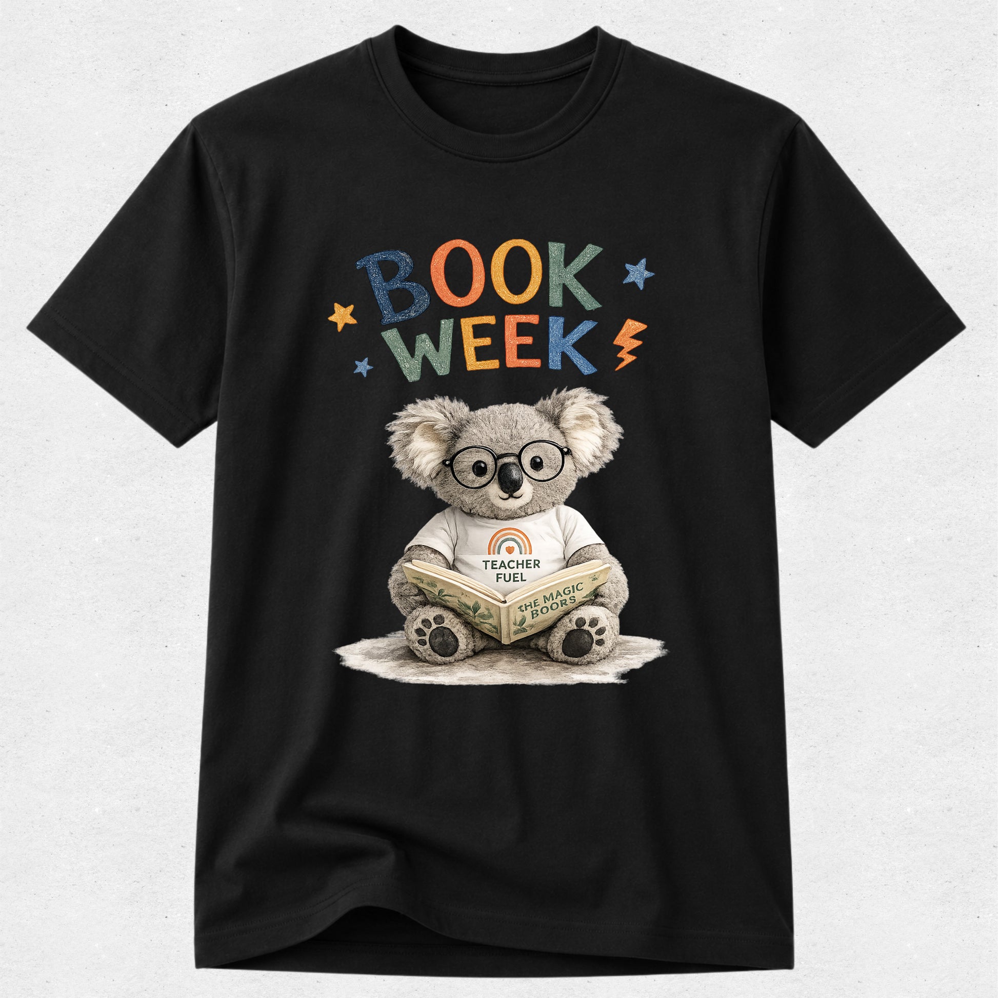 A black short-sleeve crewneck t-shirt featuring a colorful graphic of a cartoon koala wearing glasses and a white 'Teacher Co.' t-shirt, reading a book.