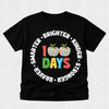 A black short-sleeve t-shirt with a colorful graphic celebrating 100 days. The design features two striped apples with green leaves, the number '100' in red and green, the word 'DAYS' in multicolor letters, and white text arched around them reading 'SMARTER • BRIGHTER • KINDER • STRONGER'.