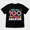 A black short-sleeve t-shirt with a colorful graphic on the front that reads 'Little Miss 100 days SMARTER' with donut, swirl, pencil, and star illustrations, shown on a light gray background.