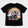 A black short-sleeve t-shirt with a colorful graphic celebrating '100th Day of School' featuring a rainbow, clouds, hearts, and an apple on a light gray background.