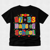 A black short-sleeve t-shirt with a colorful graphic reading '67 + 33 Days of School' in playful multicolor lettering, decorated with school-themed motifs like an apple, pencil, and stars, shown on a light gray textured background.