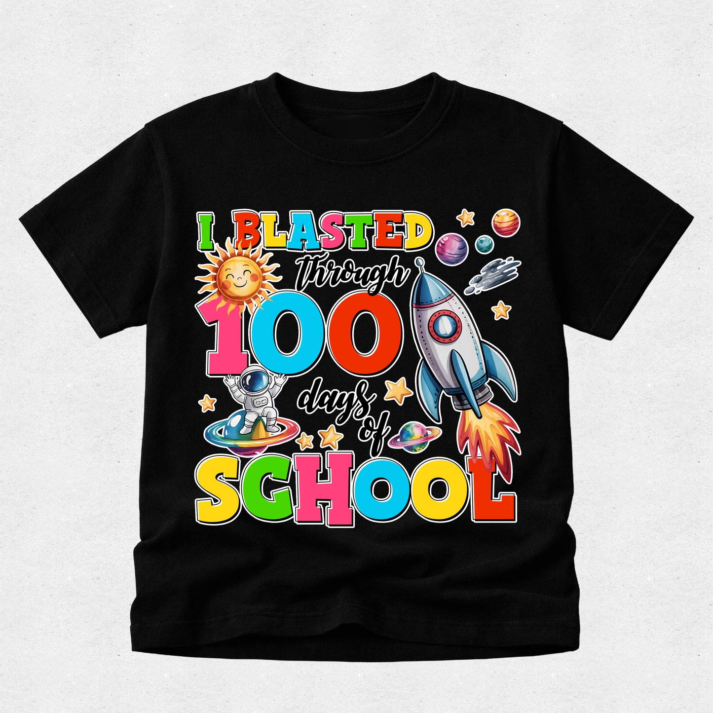 A black short-sleeve t-shirt with a colorful retro graphic celebrating '100 days of SCHOOL' with space-themed illustrations like a rocket, astronaut, and sun, displayed on a light gray textured background.
