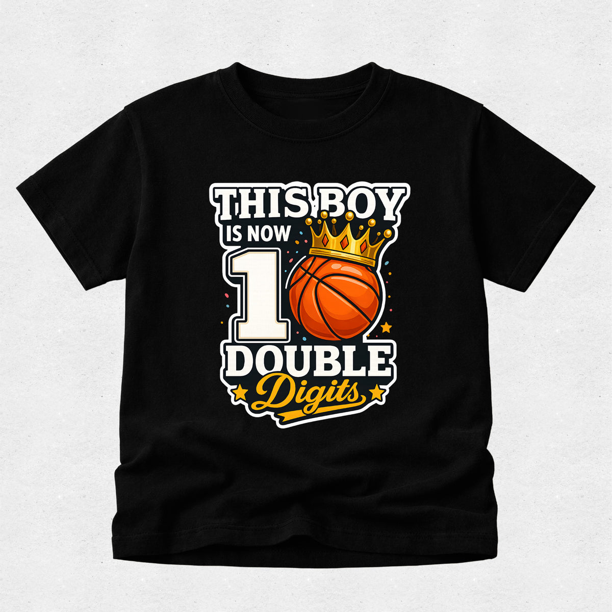 A black short-sleeve t-shirt with a graphic print that reads 'THIS BOY IS NOW 1 DOUBLE Digits' around an orange basketball with a gold crown, displayed on a light gray textured background.