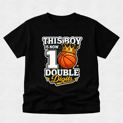 A black short-sleeve t-shirt with a graphic print that reads 'THIS BOY IS NOW 1 DOUBLE Digits' around an orange basketball with a gold crown, displayed on a light gray textured background.