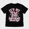 A black short-sleeve t-shirt with a pink and silver graphic celebrating a 10th birthday with a disco ball motif, shown on a light gray textured background.