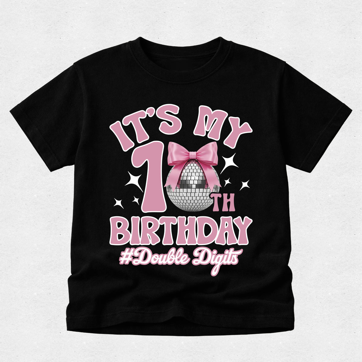 A black short-sleeve t-shirt with a pink and silver graphic celebrating a 10th birthday with a disco ball motif, shown on a light gray textured background.