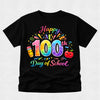 A black short-sleeve t-shirt with a colorful 'Happy 100th Day of School' graphic on the front, featuring a rainbow pencil, smiling apple, and confetti details, displayed on a light gray textured background.