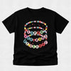 A black short-sleeve t-shirt with a colorful graphic on the front that reads 'HAPPY 100 DAYS OF SCHOOL' in pastel-colored letter circles and decorative ribbon details, shown against a light gray background.
