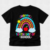 A black short-sleeve t-shirt with a colorful graphic design celebrating '100th Day of School'. The design features a vibrant rainbow, a red apple, two white clouds, a smiling sun, and the text 'HAPPY 100TH DAY OF SCHOOL' in multicolored letters, displayed on a light gray textured background.