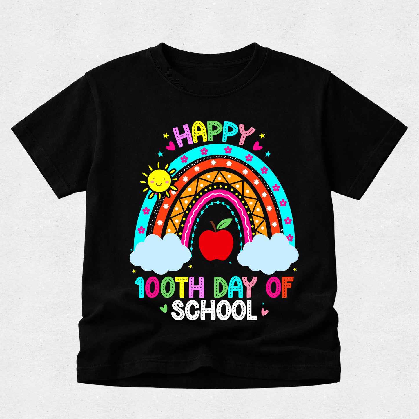 A black short-sleeve t-shirt with a colorful graphic design celebrating '100th Day of School'. The design features a vibrant rainbow, a red apple, two white clouds, a smiling sun, and the text 'HAPPY 100TH DAY OF SCHOOL' in multicolored letters, displayed on a light gray textured background.