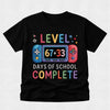 A black short-sleeve t-shirt with a colorful video game graphic that reads 'LEVEL 67+33 DAYS OF SCHOOL COMPLETE' on a light gray background.