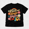 A black short-sleeve t-shirt with a retro 1960s-style graphic that reads 'Peace out Single Digits I'm 10' in colorful retro lettering, accompanied by flowers, a peace sign, and a rainbow, shown on a light gray textured background.