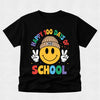 A black short-sleeve t-shirt with a colorful graphic on the front. The graphic features a yellow smiley face wearing a tan beanie with '100' on it, making peace signs with both hands, surrounded by the text 'HAPPY 100 DAYS OF SCHOOL' in rainbow colors.