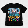 A black short-sleeve t-shirt with a colorful graphic celebrating '100 jawsome Day's of School' featuring a shark in a life preserver and school-themed icons, shown on a light gray background.