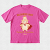 A bright pink short-sleeve t-shirt with a custom graphic on the front. The graphic features two cartoon teddy bears, one wearing a red cape and the other sitting on its shoulders, with the text 'FATHERS DAY' above and 'Daddy & Charlotte 2026' below in a warm orange-brown font.