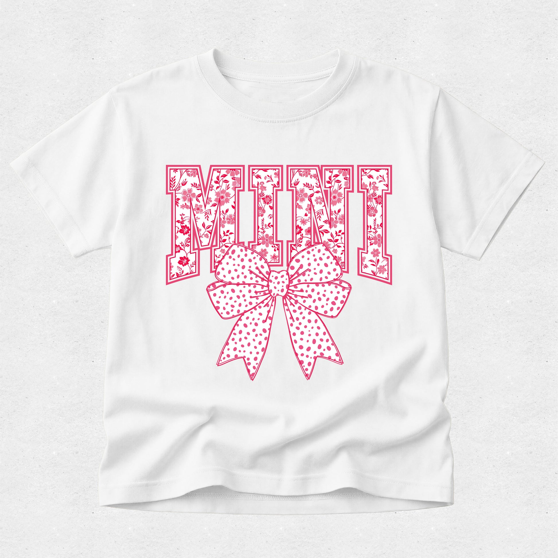 White t-shirt with pink floral 'MINI' and bow design on a white background