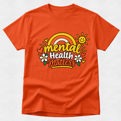 An orange crewneck t-shirt featuring a colorful retro-style graphic on the chest that reads 'mental health matters' with a rainbow, smiling sun, and flowers, displayed on a light gray textured background.
