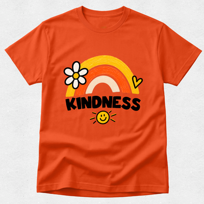 An orange short-sleeve crewneck t-shirt featuring a colorful graphic on the front with a rainbow, a daisy flower, a heart, a smiley face, and the word 'KINDNESS' in black text, displayed against a light gray textured background.