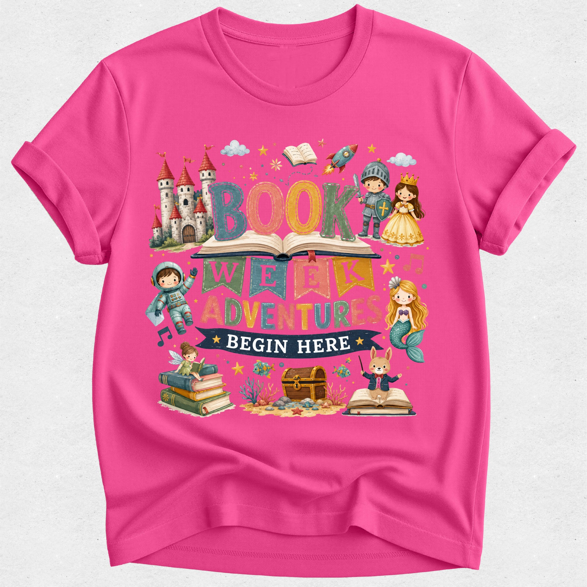 A bright pink short-sleeve t-shirt with a colorful cartoon graphic on the front. The graphic features the words 'BOOK WANDERER ADVENTURES BEGIN HERE' surrounded by whimsical illustrations of a castle, an open book, a rocket, a wizard, a princess, a mermaid, a fairy, a treasure chest, and a fox.