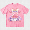 A pink short-sleeve crewneck t-shirt featuring a graphic of a pink and purple fairy tale costume dress with the text 'THIS IS MY BOOK WEEK COSTUME!' printed on the front, displayed flat against a light gray background.