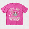 A bright pink short-sleeve t-shirt with a '1st Birthday' graphic on the front, featuring a pink bow, disco ball, and the text '#Double Digits' on a light gray textured background.