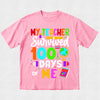 Pink t-shirt with colorful text 'My teacher survived 100 days of me' on a light gray background