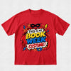 A red short-sleeve crewneck t-shirt featuring a colorful comic book style graphic that reads 'THIS IS MY BOOK WEEK COSTUME!' with a superhero mask, cape, and comic-style text elements.