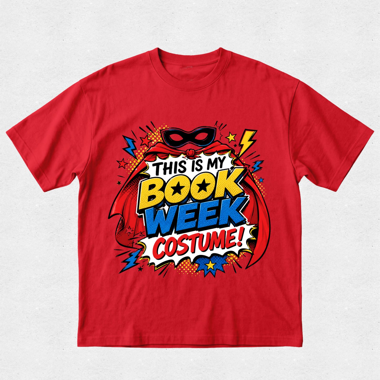 A red short-sleeve crewneck t-shirt featuring a colorful comic book style graphic that reads 'THIS IS MY BOOK WEEK COSTUME!' with a superhero mask, cape, and comic-style text elements.