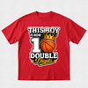 A red short-sleeve crewneck t-shirt with a graphic print on the front. The graphic features the text 'THIS BOY IS NOW 10 DOUBLE Digits' in white, black, and yellow lettering, accompanied by an illustration of an orange basketball wearing a gold crown.
