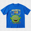 A bright blue short-sleeve t-shirt with a colorful graphic on the front reading 'JAMES'S 100 DAYS OF SCHOOL! 100 EYES LEARNING!' above and below a green cartoon monster with many eyes, shown on a light gray background.