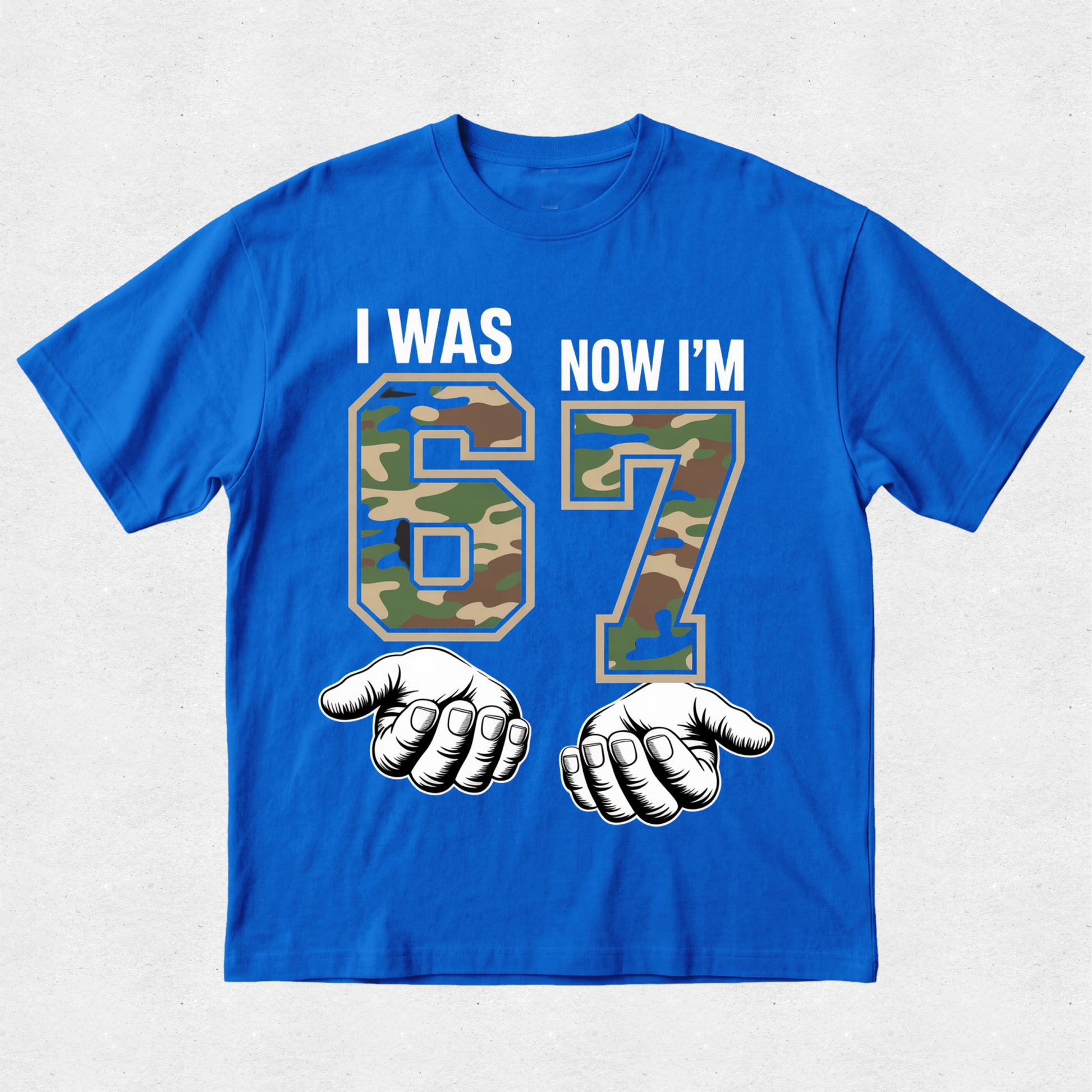Blue t-shirt with camouflage numbers '6' and '7' and text 'I WAS 6 NOW I'M 7' on a light gray background