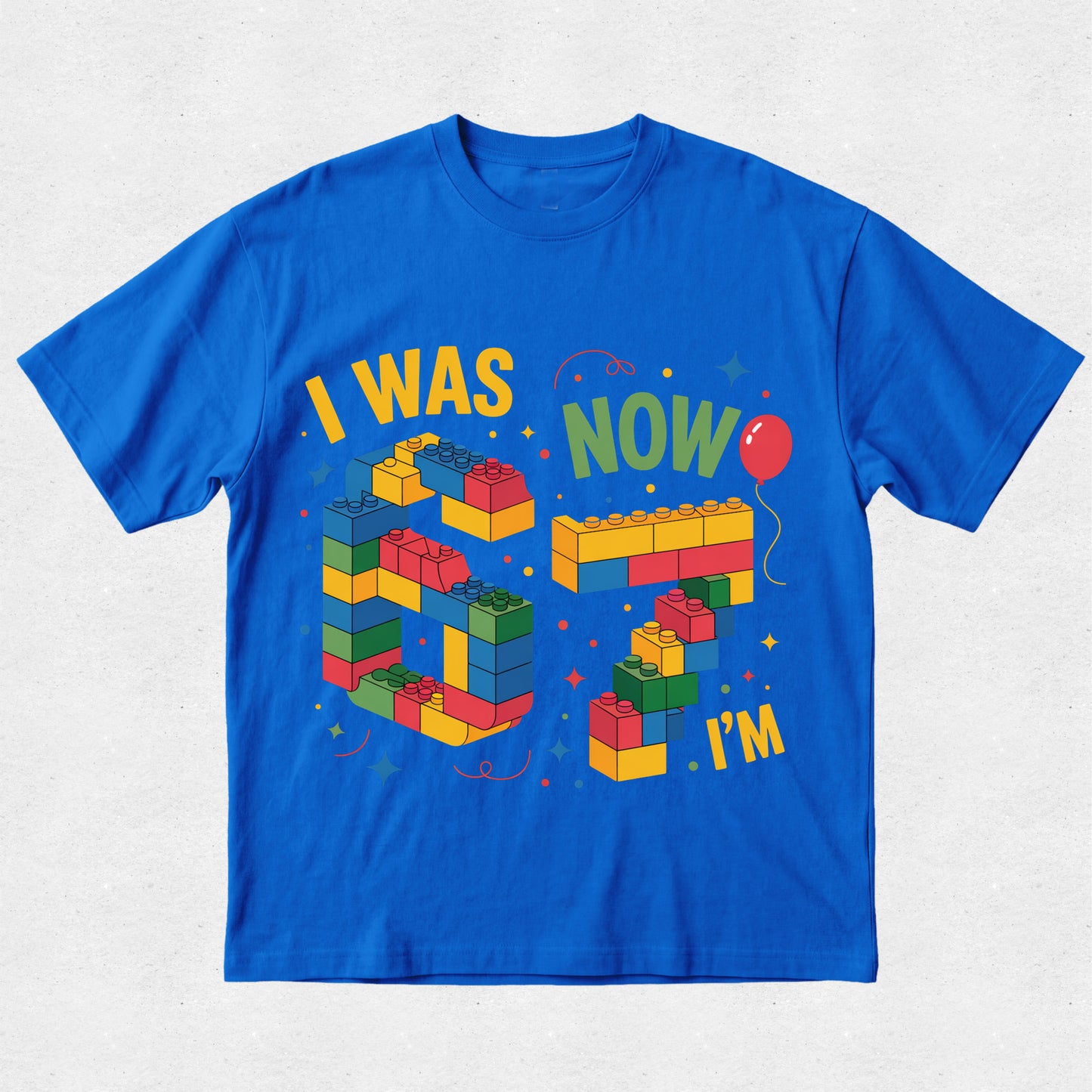 Blue t-shirt with colorful building block design and text on a light gray background