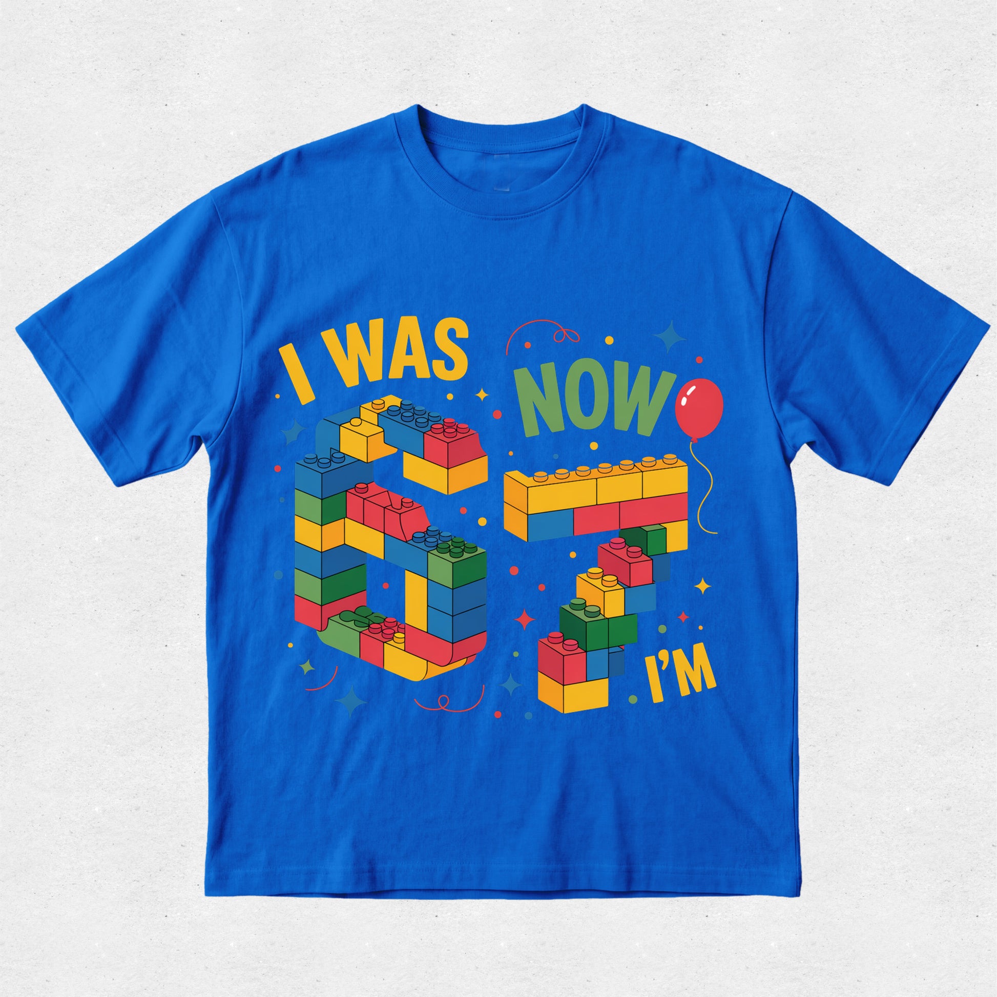 Blue t-shirt with colorful building block design and text on a light gray background