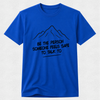 A royal blue short-sleeve crewneck t-shirt with a black line art mountain graphic and the text 'BE THE PERSON SOMEONE FEELS SAFE TO TALK TO' printed on the chest, displayed against a light gray textured background.